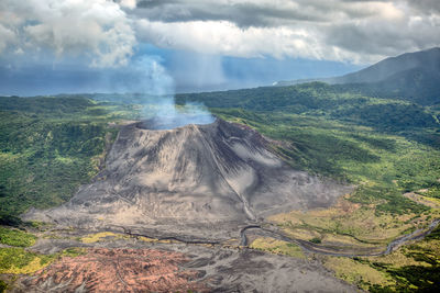Smoke emitting from volcanic landscape against sky