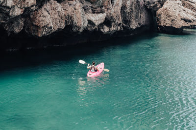 Kayak people in the clear blue sea near the cliffs.