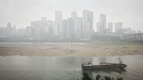 Scenic view of river in city against sky