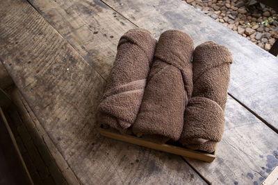 Three brown towels folded into a cylinder are placed on a wooden table. prepared