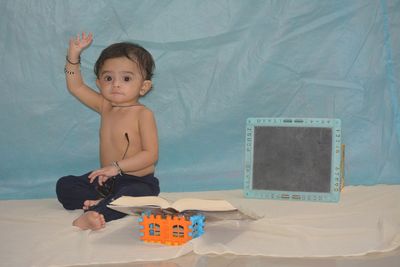 Boy playing with toy sitting on bed at home