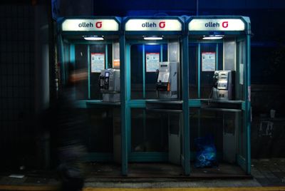 Illuminated telephone booth in city at night