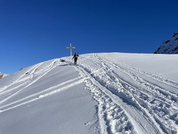 Rear view of man skiing on snowcapped mountain against clear blue sky