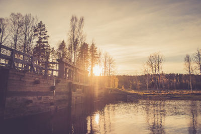 Footbridge over canal against sky during sunset