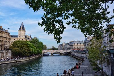 People on pier by seine river in city against sky