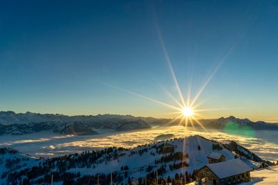 Scenic view of snow mountains against blue sky during sunset