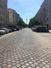 Cobblestone street amidst buildings in city against sky