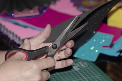 Cropped hands of person cutting paper on table