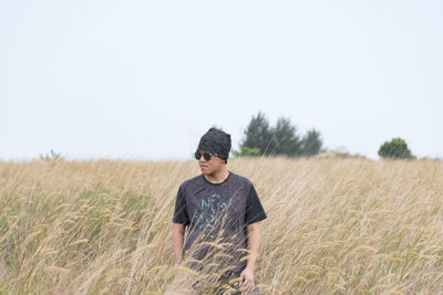 Man standing on wheat field against clear sky