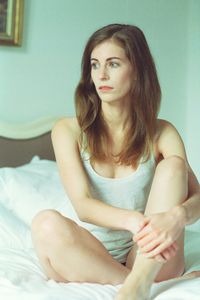 Portrait of young woman sitting on bed