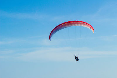 Low angle view of person paragliding against blue sky during sunny day