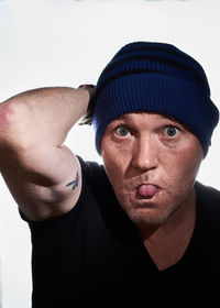 Close-up portrait of man sticking out tongue against white background