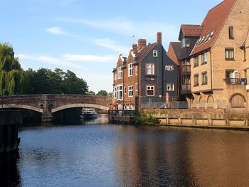 Arch bridge over river amidst buildings against sky