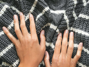 Woman's hands on gray knitted sweater with white stripes. folded warm clothing. crumpled textile.