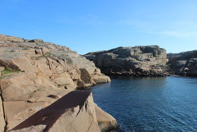 Rock formations by sea against sky