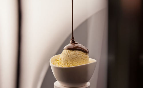 Close-up of chocolate syrup pouring on ice cream in bowl