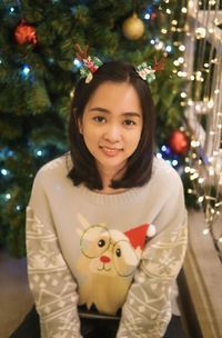 Portrait of young woman standing by christmas tree