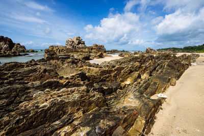 Rocks at beach against sea and sky