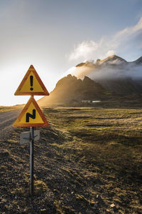 Road sign by mountains against sky