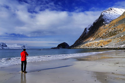 Rear view of man standing on beach against sky