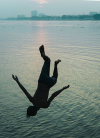 Man jumping in sea against sky