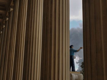 Low angle view of man standing on wood against sky