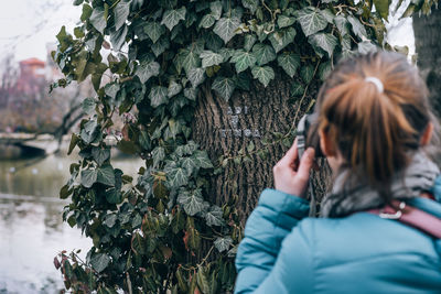 Close-up of woman photographing with mobile phone on tree