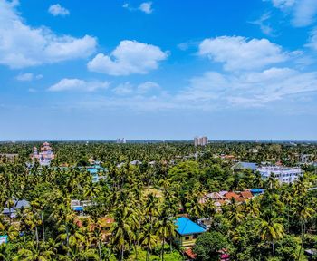 High angle view of trees and buildings against blue sky