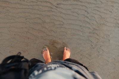 Low section of man standing on sand at beach