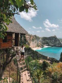 Woman standing on ladder against sea