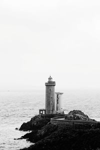 Lighthouse on building by sea against sky