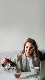 Portrait of young woman using mobile phone while sitting on snow