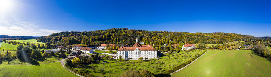 Panoramic view of trees and buildings against blue sky