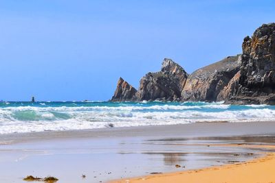 Scenic view of beach against clear blue sky