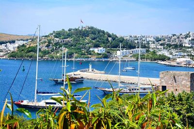 Boats moored in river by city against sky