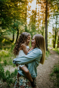 Happy mother holding young girl in forest