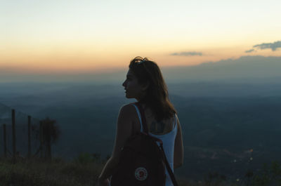 Woman looking away against sky during sunset