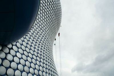 Low angle view of modern building against cloudy sky