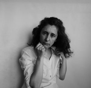 Portrait of young woman standing against wall