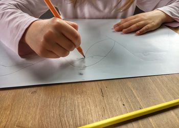 Midsection of child making sketch on paper 