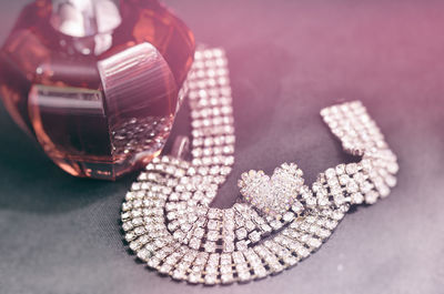 High angle view of diamond necklace and perfume on table