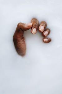 Dark skin hand in the milky smooth water substance