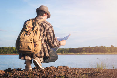 Side view of man standing at lakeshore against sky