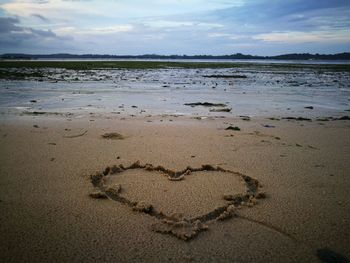 Heart shape on beach against sky