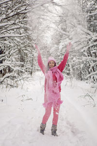 Woman raise your hands up. woods in pink clothes a jacket a knitted scarf. snowy forest in winter
