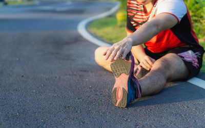 Low section of man holding umbrella on street