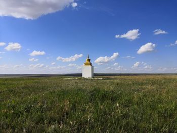 Lighthouse on field against sky