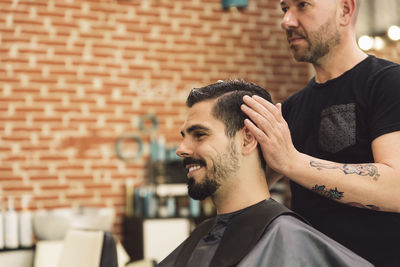 Barber dressing man hair in salon