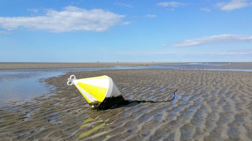 Buoy on beach against sky