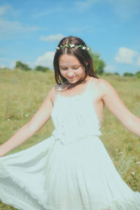 Teenage girl holding white dress while standing on field during sunny day